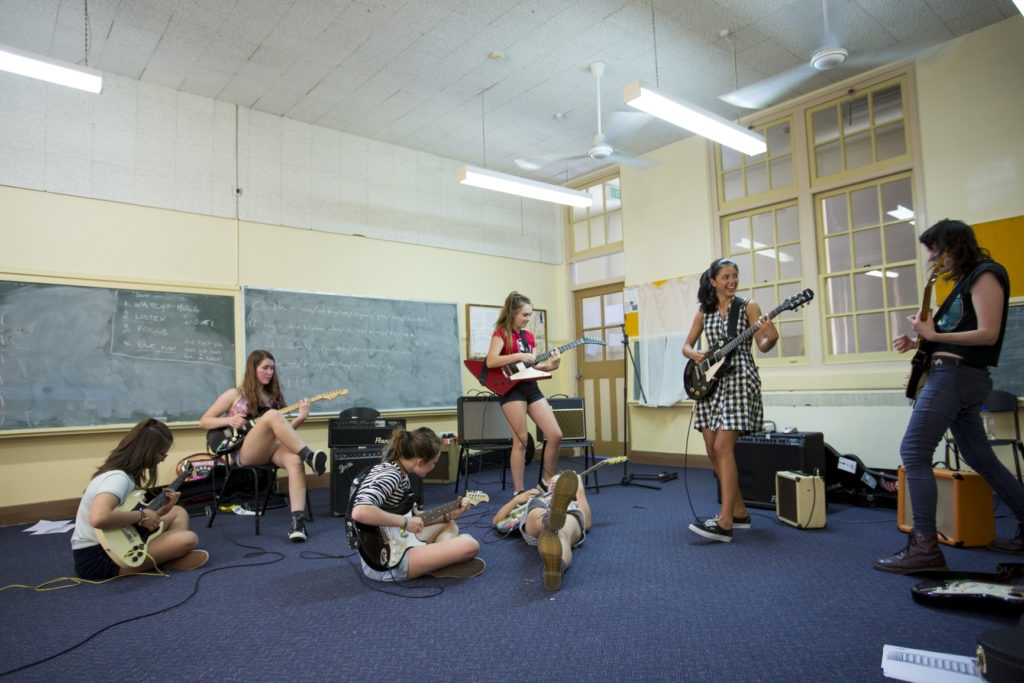 A group of five young women playing guitars.