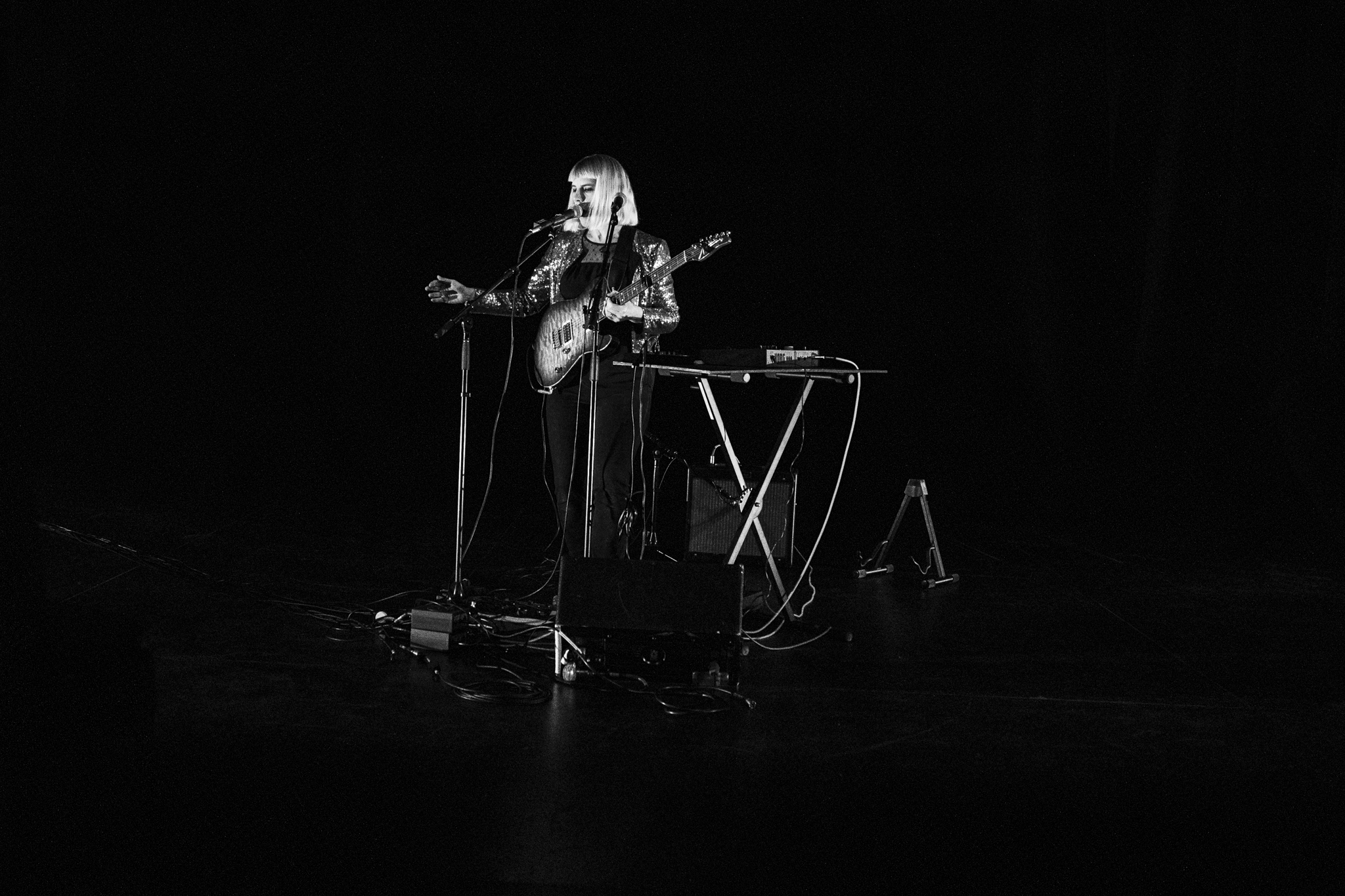 Gorman Sessions: A woman standing under a spotlight holding a guitar