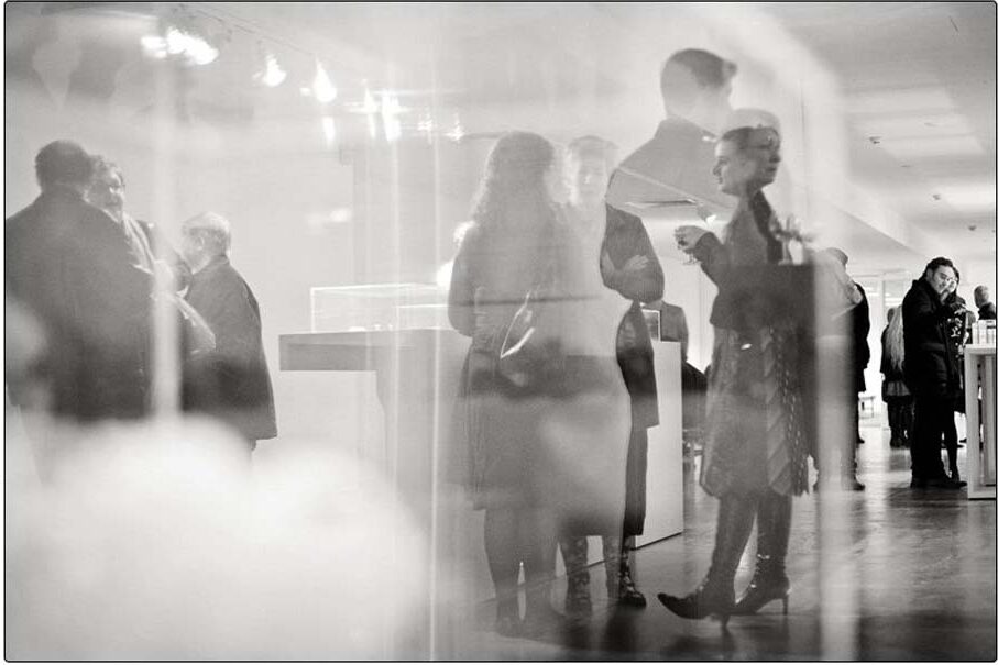 Black and white photo of people standing in an art gallery.