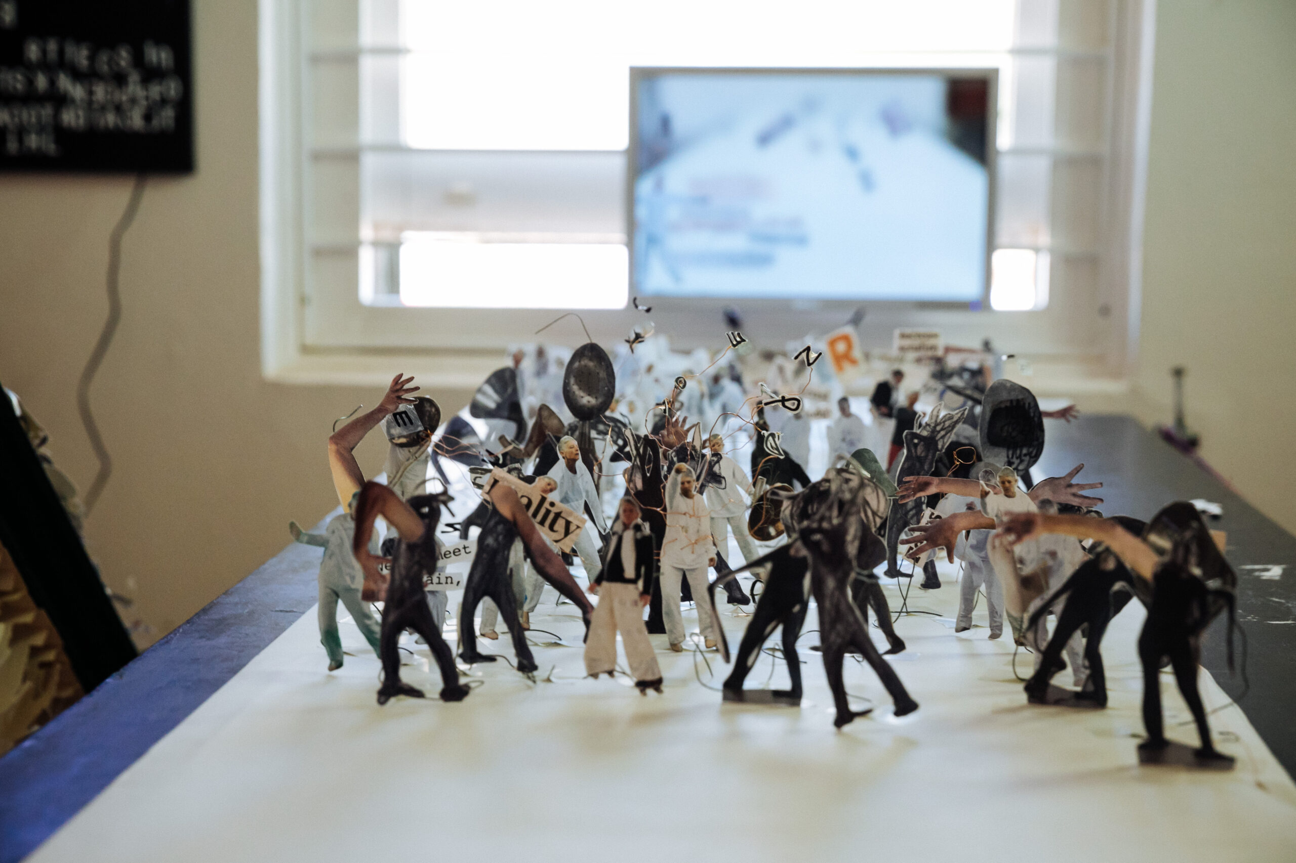 A diorama of Nikki Haynes work. It depicts small cut out people with their arms up!