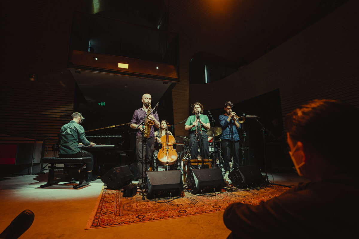 Six people playing music instruments - piano, saxophone, cello, oboe, drums and trumpet.