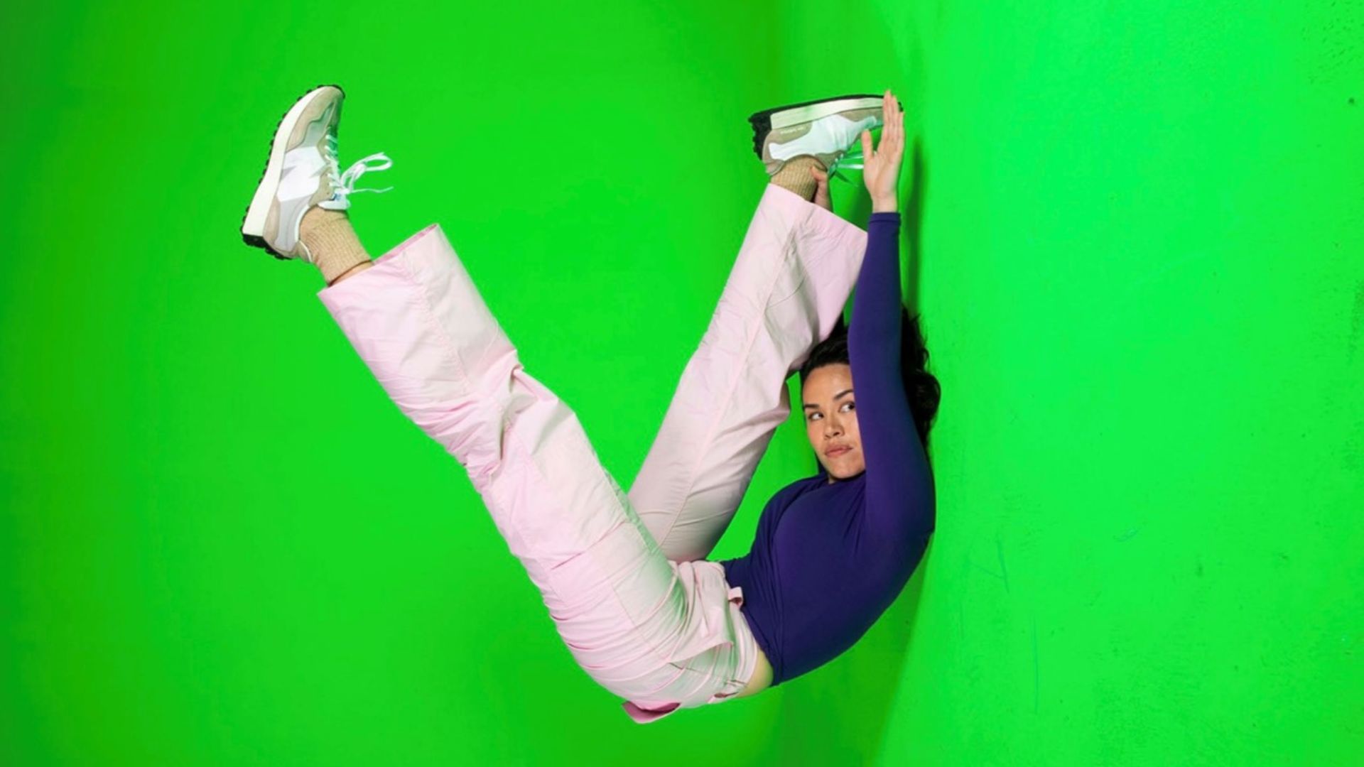 A dancer folds in half on a green background.