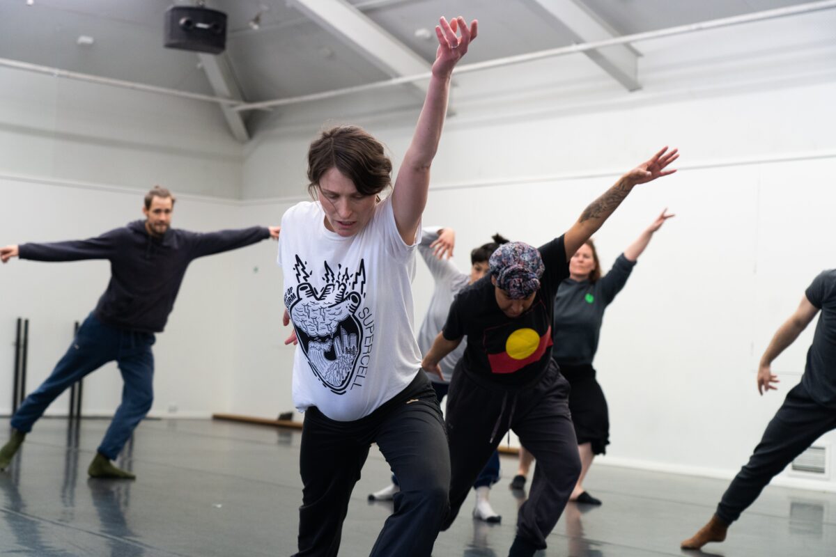 Dancers rehearse in a white-walled dance studio.