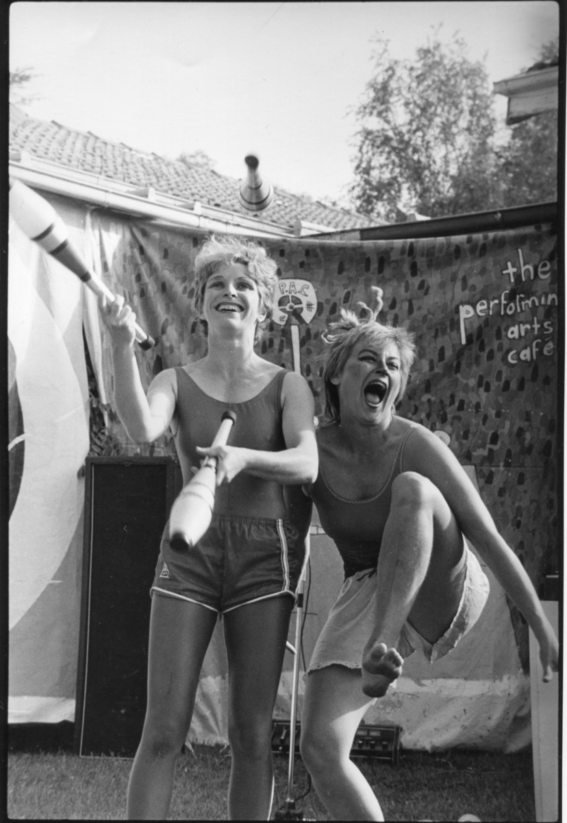 Black adn white image of two ladies performing circus tricks in front of a sign that reads 