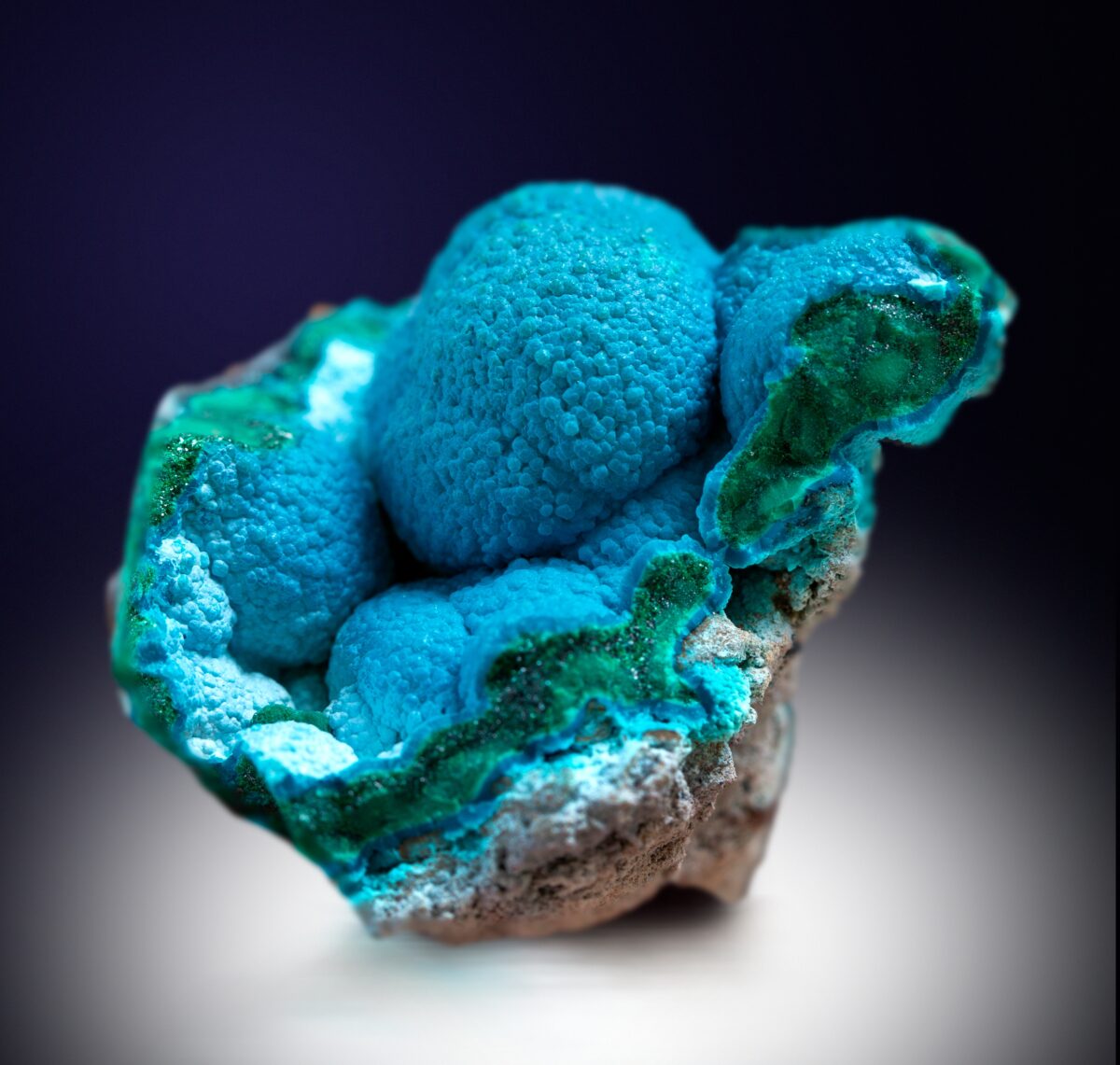 A striking teal-blue crystal sits on a black background in a spotlight.