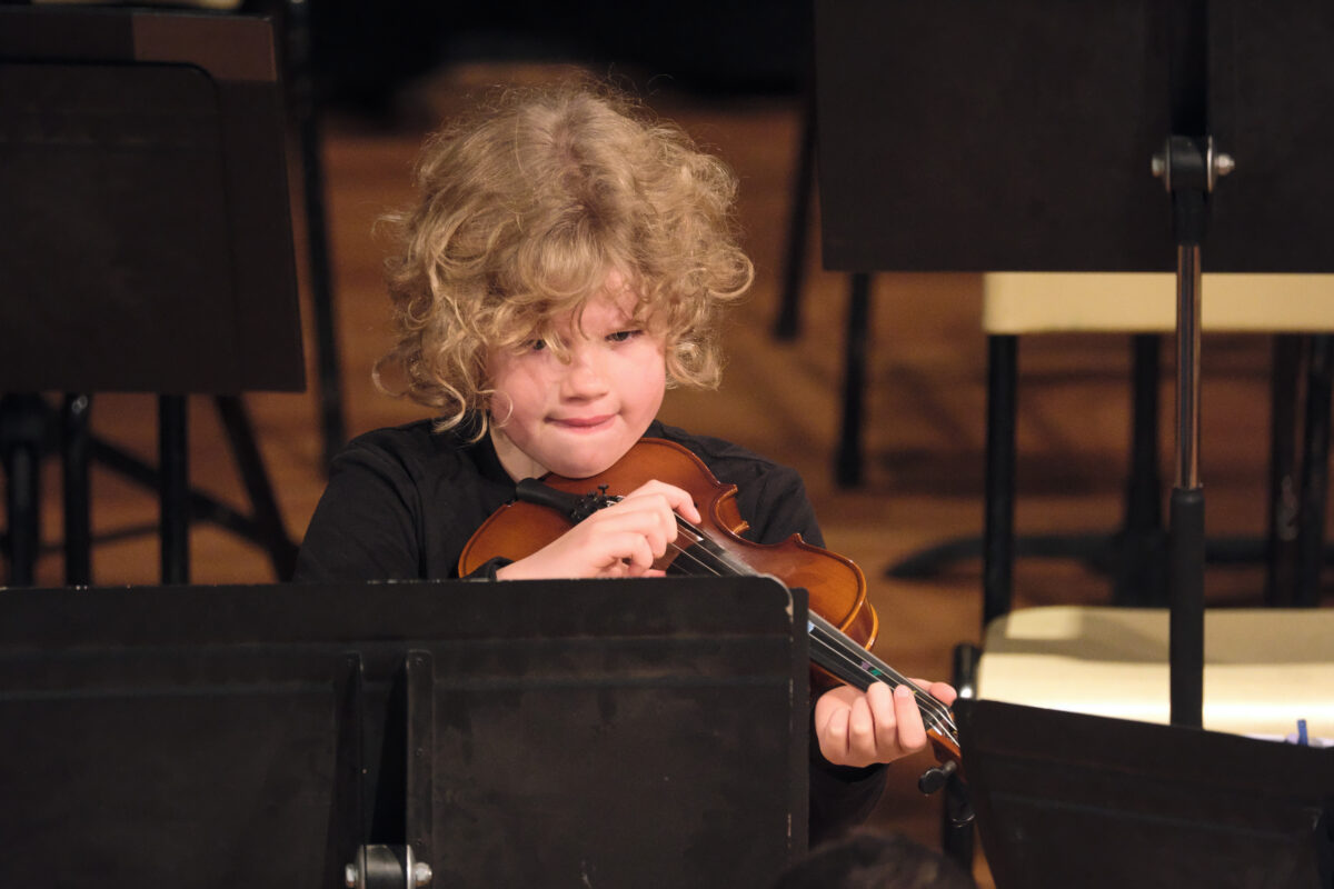20240622b 043 MfC Winter Concert – Olivia Swift A young child dressed in black playing a small violin.