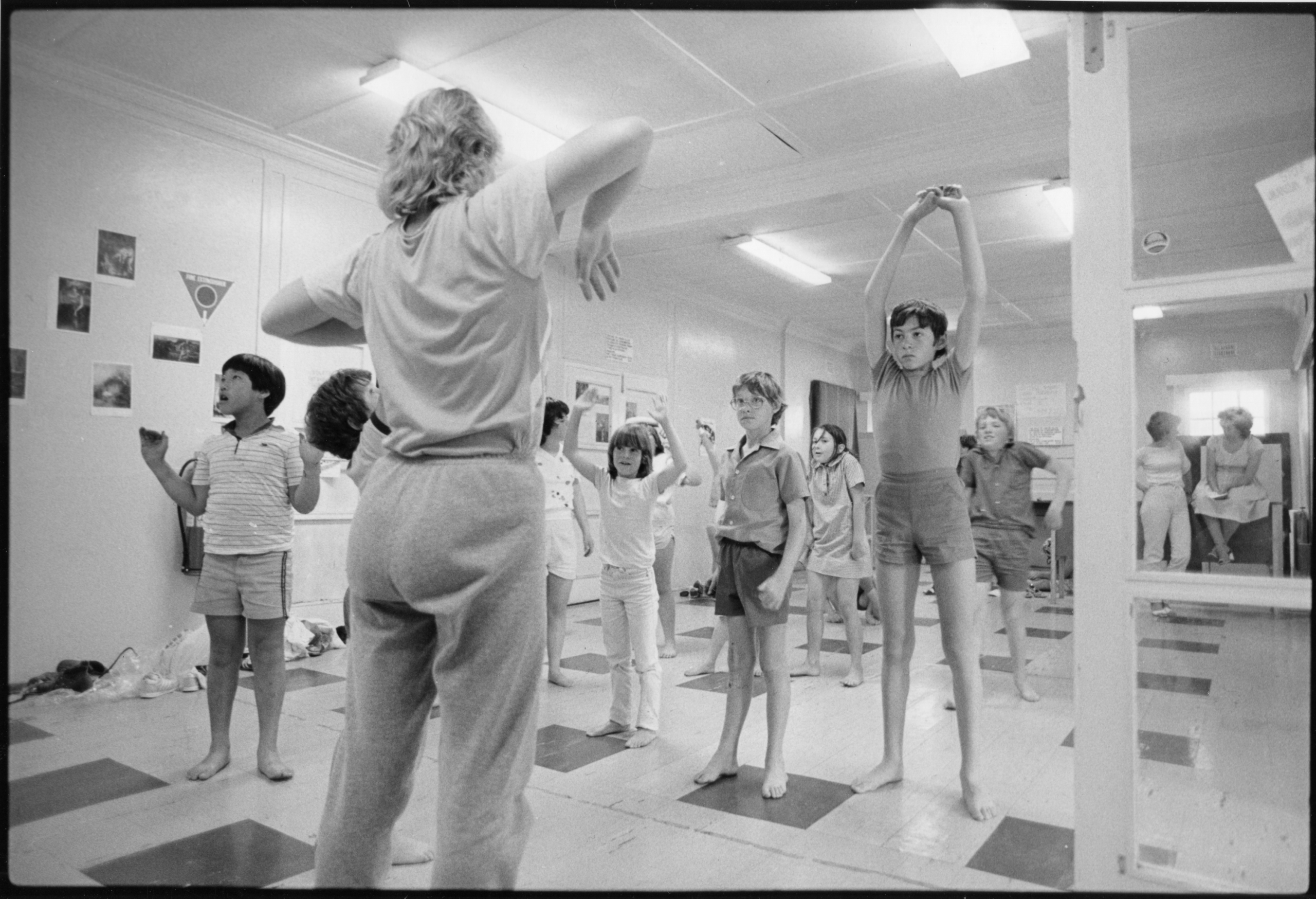 A black and white image of young dancers in a vinyl floored dance studio.