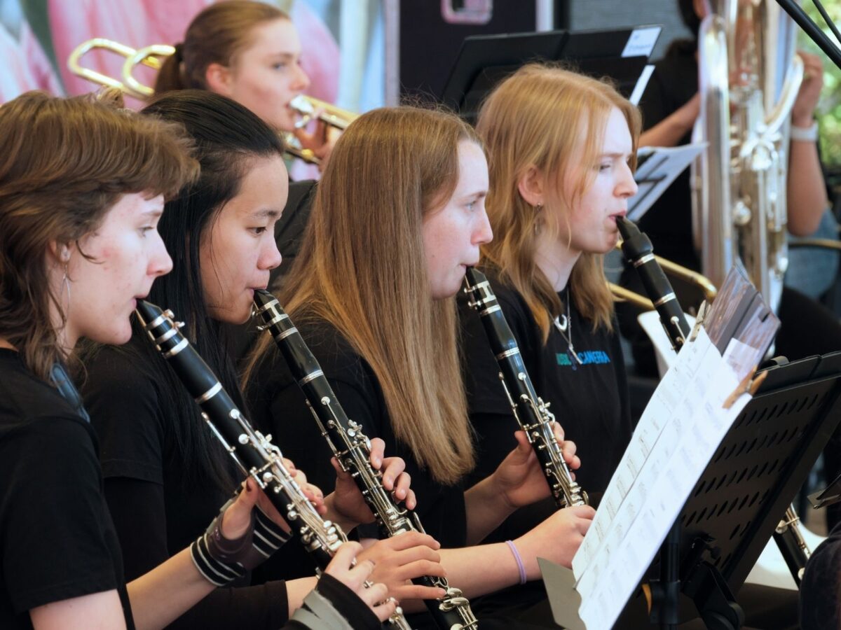 a picture of four young clarinet players reading music and playing in concert.