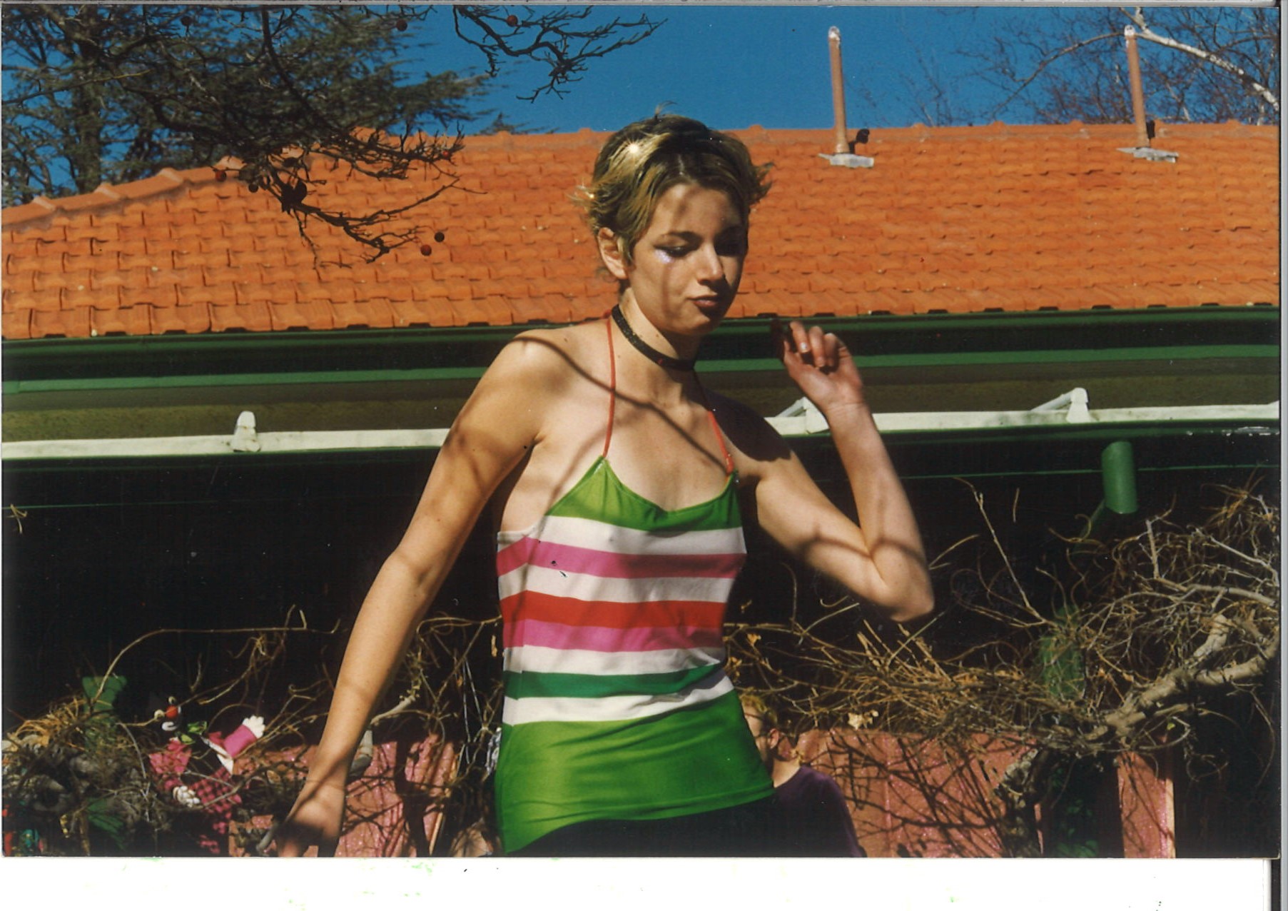 A girl with short cropped hair struts the runway in a tight green and pink shirt in the grounds of Gorman House.